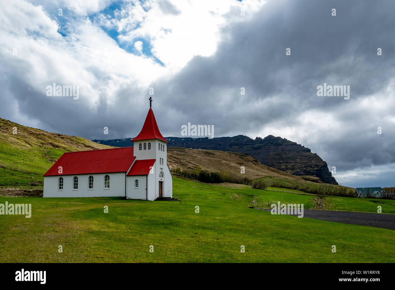 Chiesa islandese con un tetto rosso arroccato sul pendio di una collina nel sud-est dell'Islanda Foto Stock