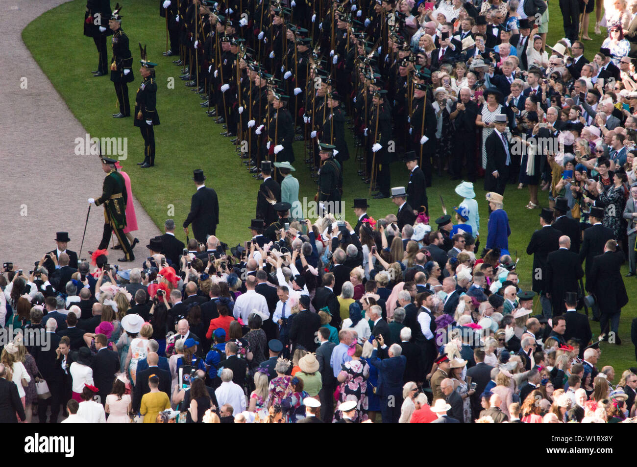 Edinburgh, Regno Unito. Il 3 luglio 2019. Sua Maestà la Regina (raffigurato in abito rosa e rosa hat) ha ospitato il suo giardino annuale festa nel Palazzo di Holyroodhouse di Edimburgo durante il Royal settimana in Scozia. Sua Maestà la Regina party in giardino era frequentato da persone di tutte le età e stili di vita. Il sun ha realizzato un aspetto fantastico e la band ha suonato musica allegra e alcune copertine di ben noti i numeri. Gli ospiti goduto il tè del pomeriggio con panini gourmet, torte e royal cioccolatini. Credito: Colin Fisher/Alamy Live News Foto Stock