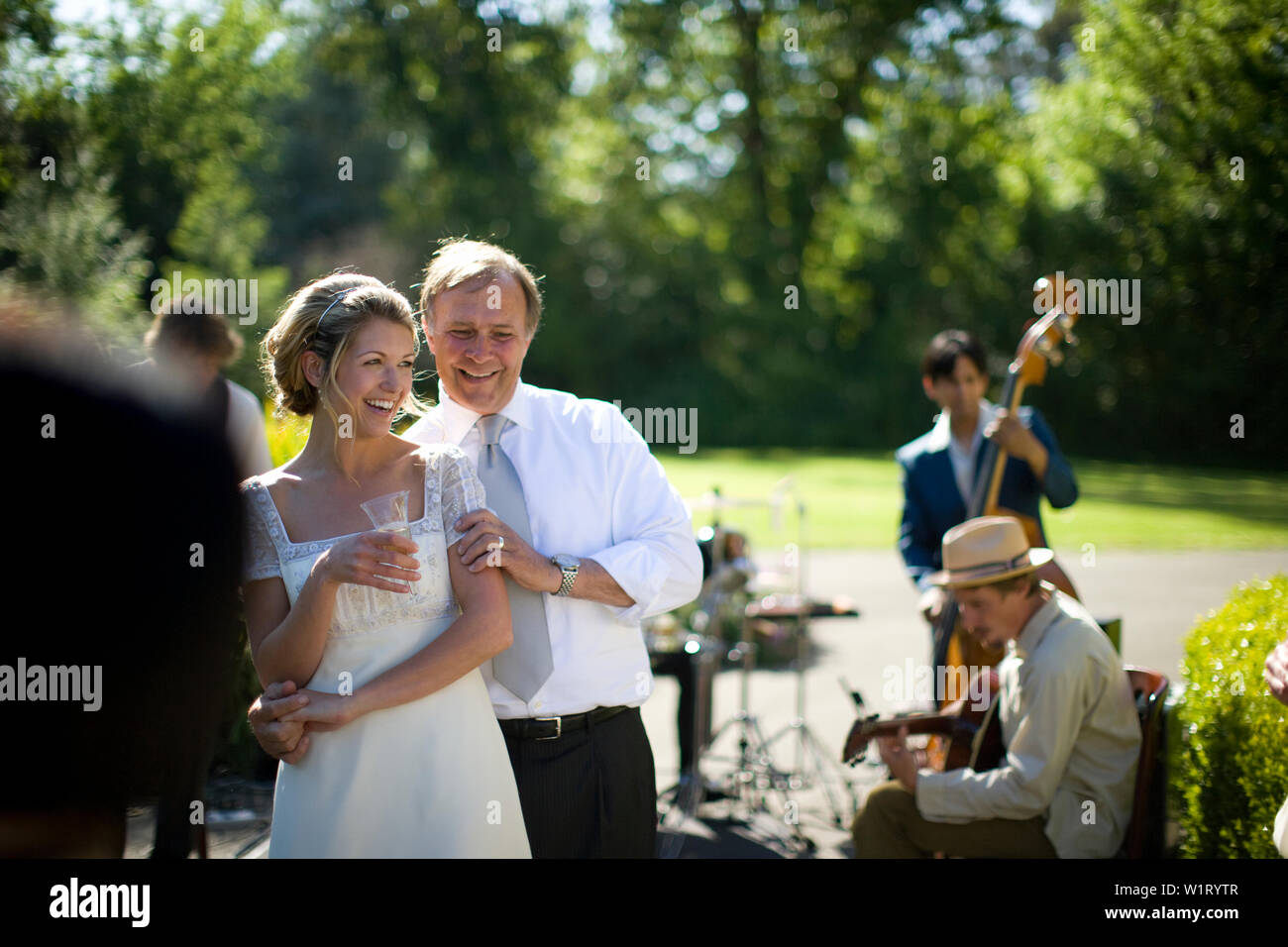 Adulto Uomo tenendo la sua giovane adulto sposa accanto a una banda musicale il giorno delle nozze. Foto Stock