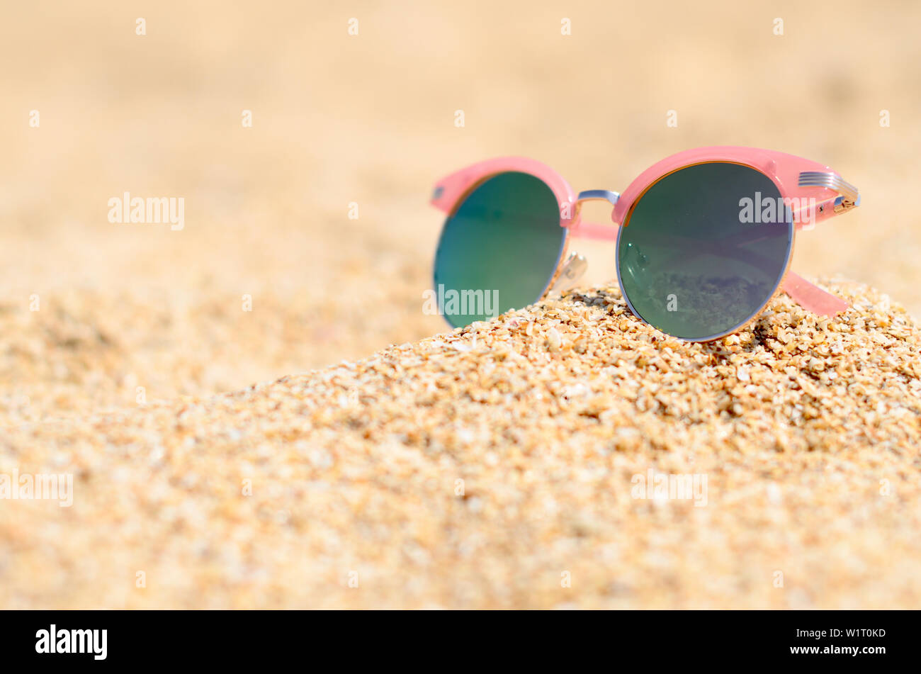 Eleganti occhiali da sole rosa in estate spiaggia di sabbia Foto Stock