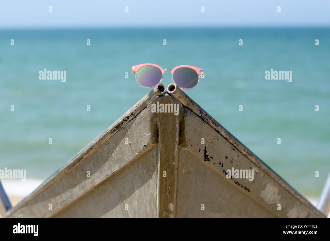 Eleganti occhiali da sole rosa su una barca vicino al mare Foto Stock