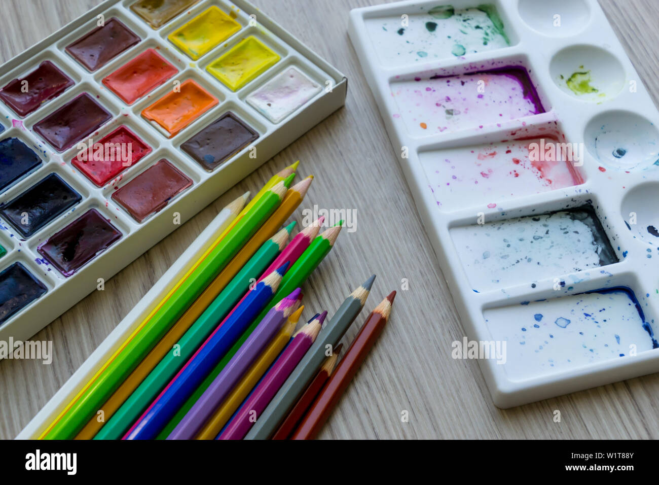 Creative educazione artistica concetto - la scatola con il set di coloratissimi acquerelli di vernice e il set di matite disegno close up Foto Stock