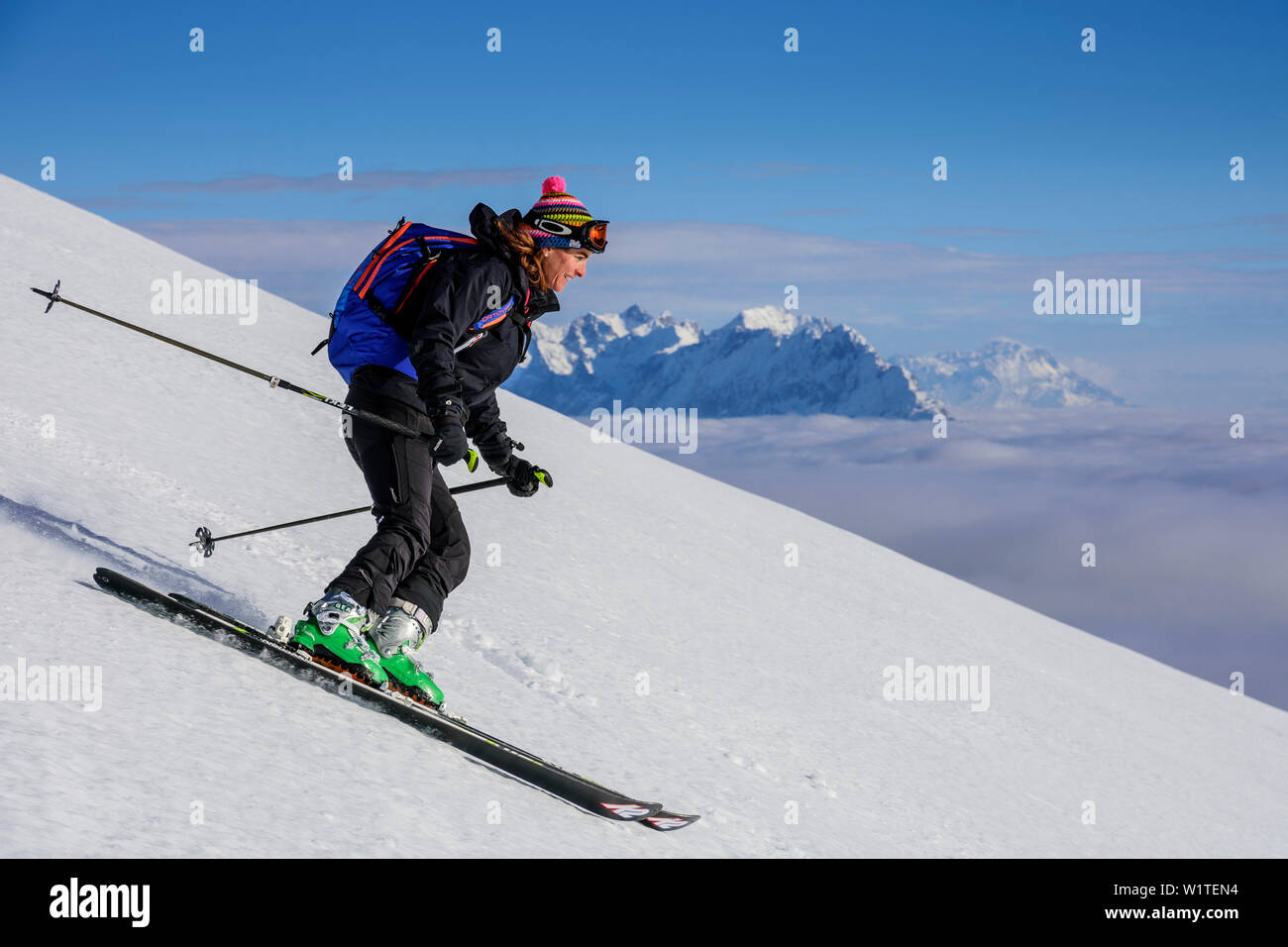 Donna sci backcountry discendente dalla Hinteres Sonnwendjoch, Kaiser gamma in background, Hinteres Sonnwendjoch, Alpi Bavaresi, Tirolo, Austria Foto Stock