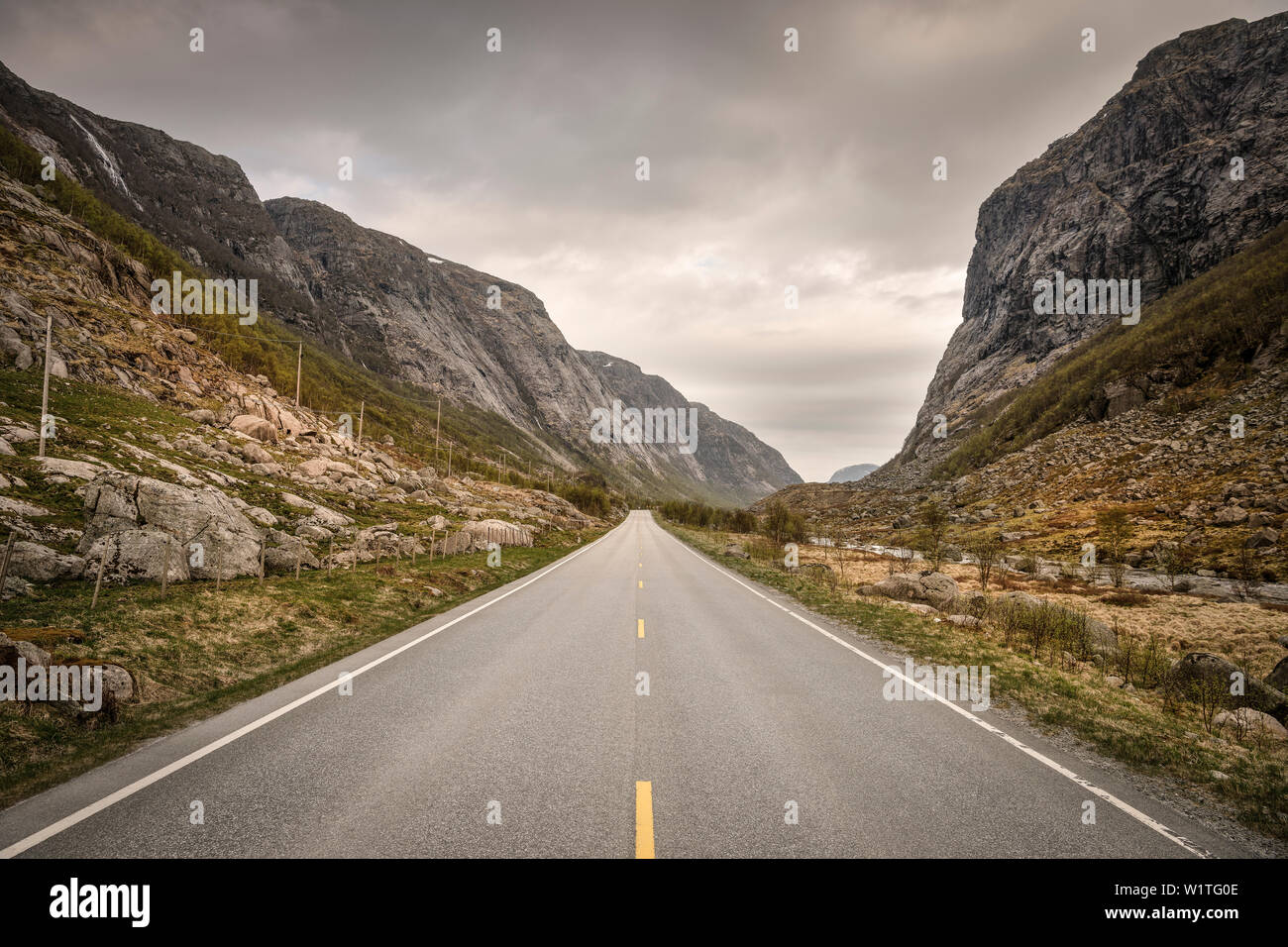 Strada conduce attraverso una profonda valle circondata da montagne, Norvegia, Scandinavia, Europa Foto Stock