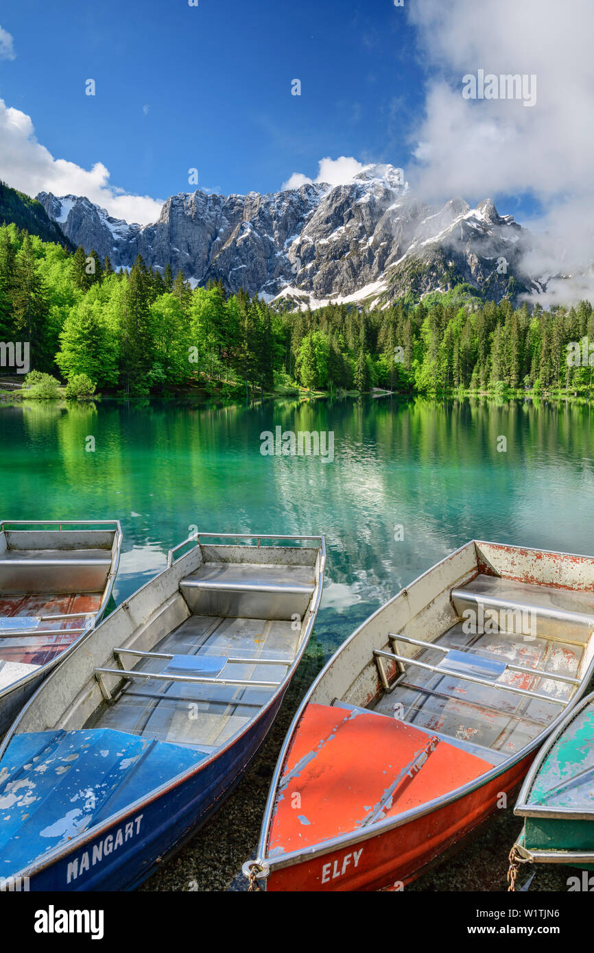 Barche colorate che stabilisce nel lago di Fusine, Mangart in background, Lago Fusine, sulle Alpi Giulie, Friuli, Italia Foto Stock