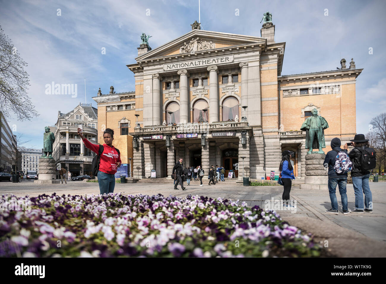 Giovane donna rendendo selfie di lei di fronte del Teatro Nazionale (Nationaltheatert), Oslo, Norvegia, Scandinavia, Europa Foto Stock