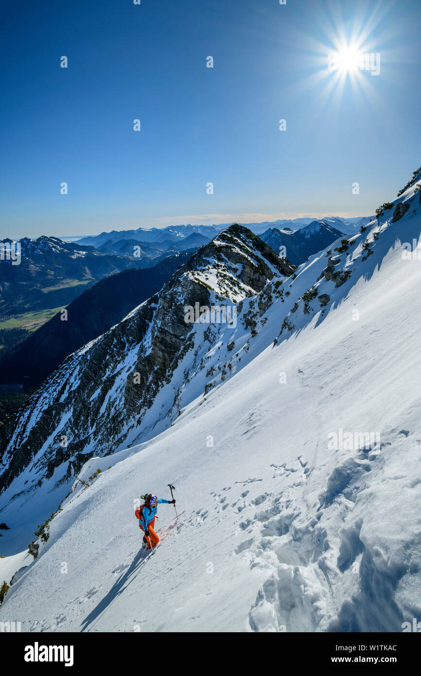 Donna backcountry-sci salendo a piedi su Steep faccia, Hochmiesing, Spitzing, Alpi Bavaresi, Alta Baviera, Baviera, Germania Foto Stock