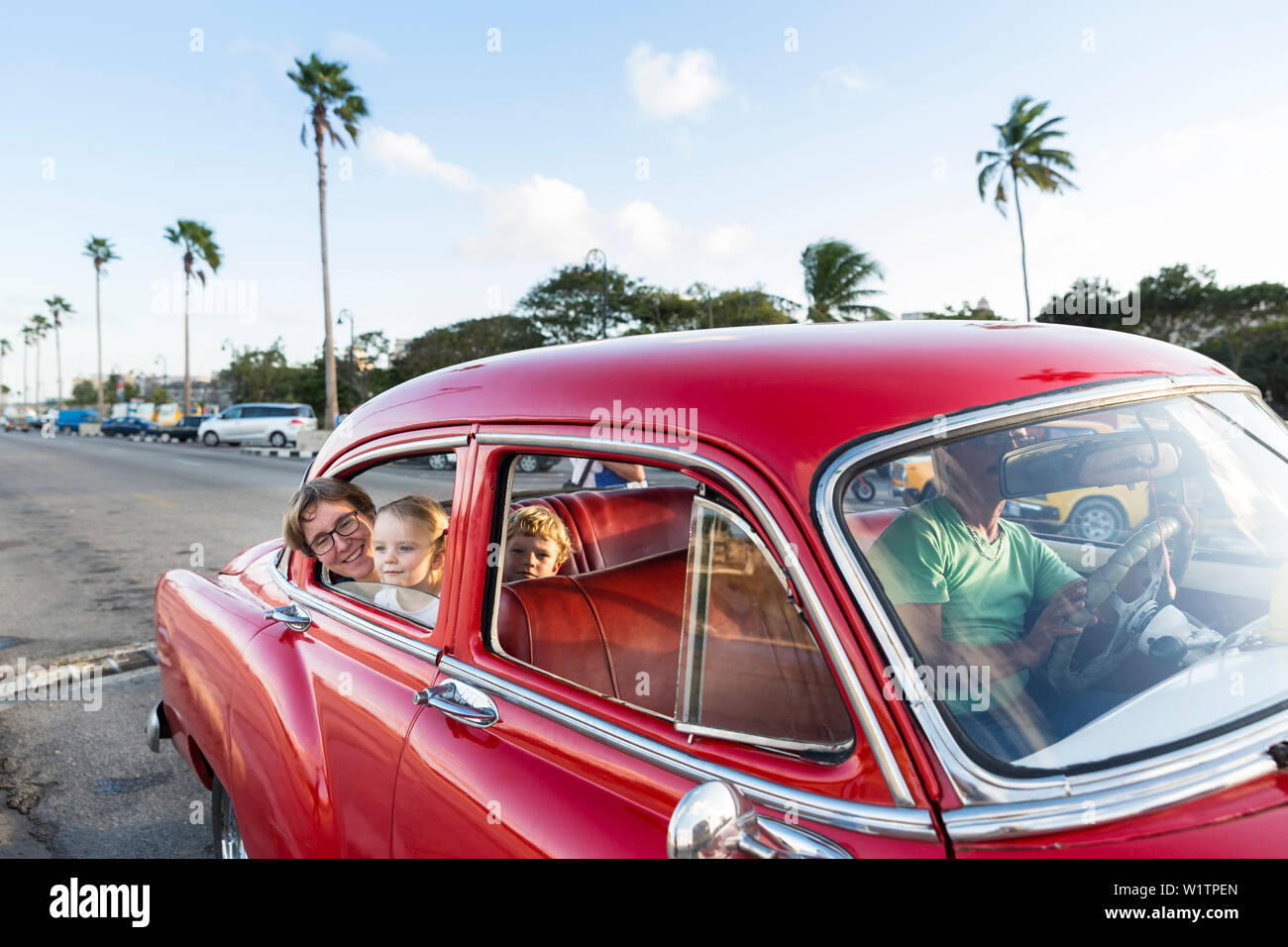 Madre con i bambini seduti in un rosso oldtimer, comodi posti a sedere, centro storico, la città vecchia, La Habana Vieja, famiglia viaggi a Cuba, i genitori con le Foto Stock