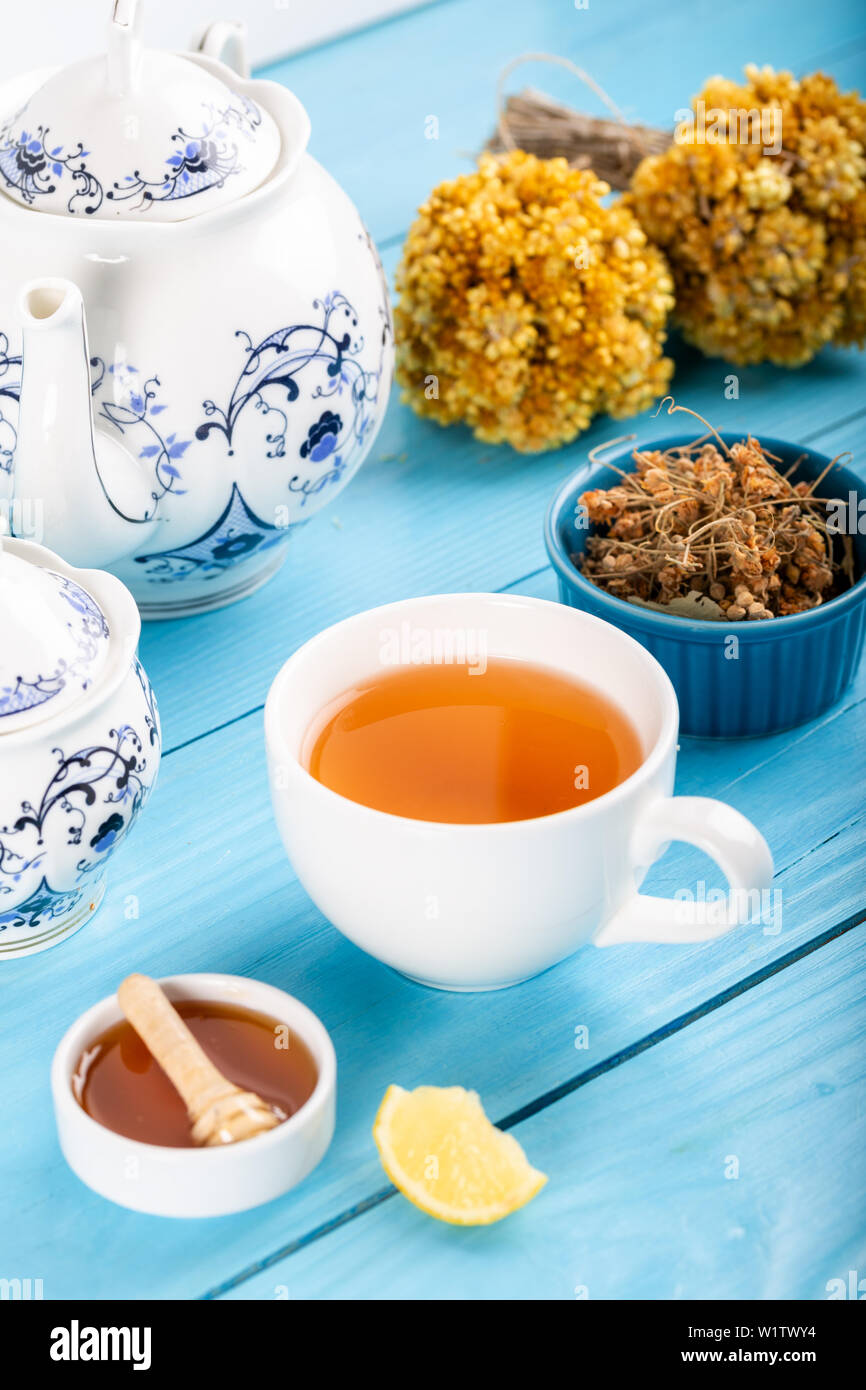 Tazza di tè di tiglio, essiccati i fiori di tiglio in tazza con miele e limone su sfondo di legno. Foto Stock