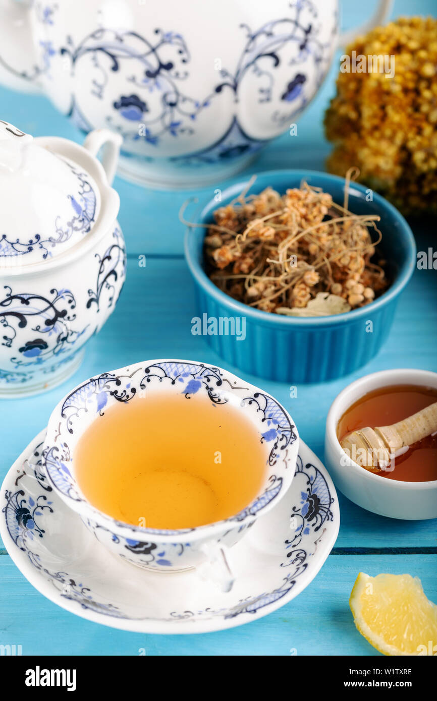 Tazza di tè di tiglio, essiccati i fiori di tiglio nella ciotola con il miele e limone su sfondo di legno Foto Stock