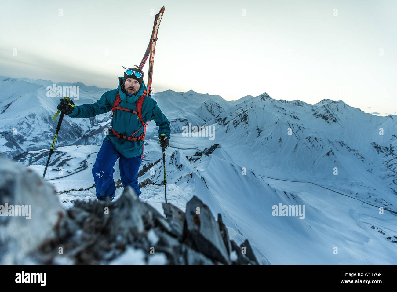 Giovane maschio sciatore hikiing fino attraverso la neve profonda ad un picco di montagna, Gudauri, Mtskheta-Mtianeti, Georgia Foto Stock
