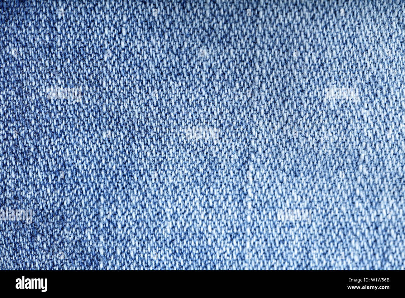 Jeans texture di sfondo - indossato pantaloni jeans tessuto lavato blu denim tessuto. Primo piano della moda di tessitura del cotone per lo sfondo o copia di spazio. Foto Stock