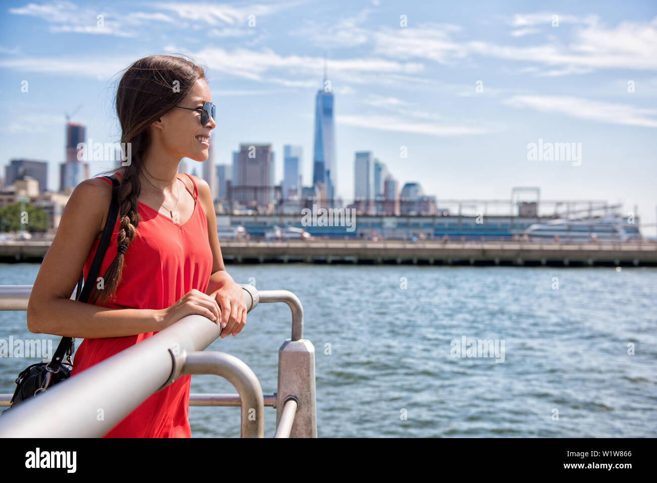 New York City travel - Tourist donna sul viaggio estivo guardando waterfront vista della skyline con un edificio a torre in background. Foto Stock