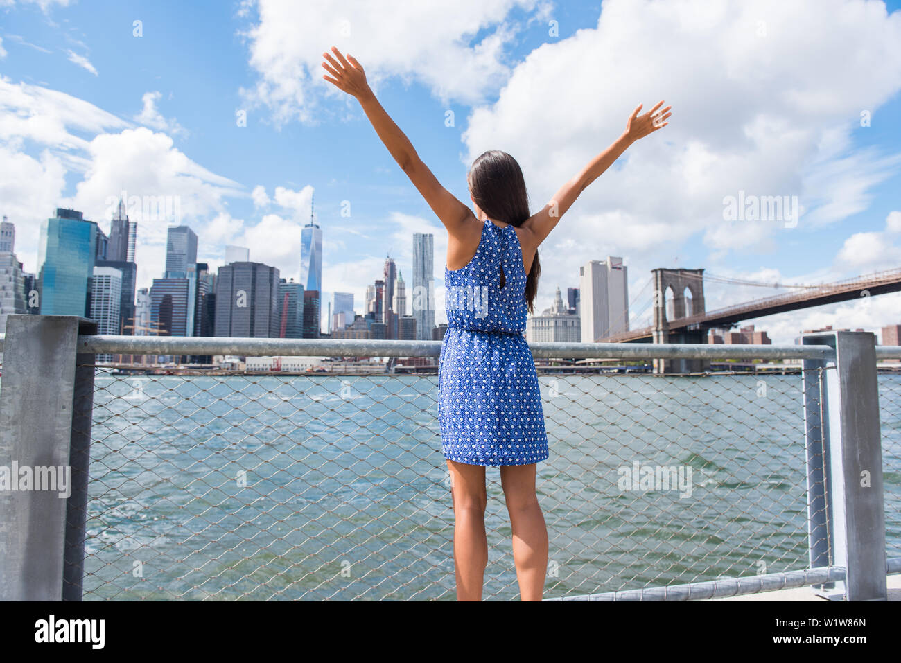 Felice donna libera il tifo a NYC New York City urban skyline con le braccia in alto sollevato nel cielo. Il successo in affari carriera, il raggiungimento degli obiettivi o di spensierata libertà urbano di successo concetto di persona. Foto Stock