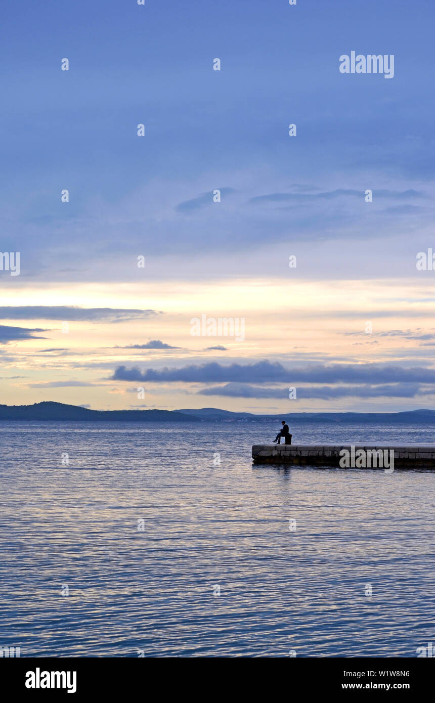 Uomo di pesca in mare (fiume) al tramonto (alba) - Zadar (Croazia) Foto Stock