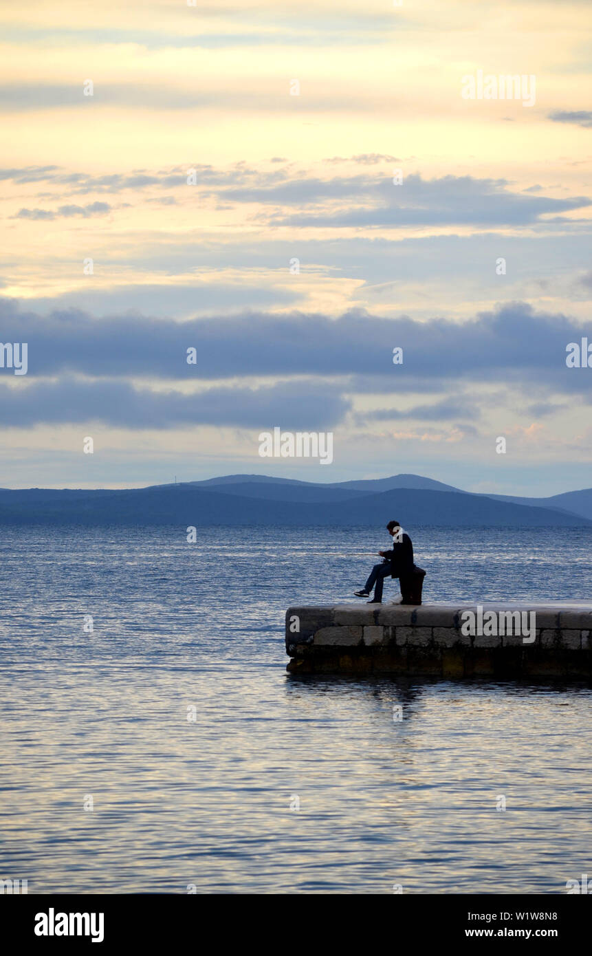 Uomo di pesca in mare (fiume) al tramonto (alba) - Zadar (Croazia) Foto Stock