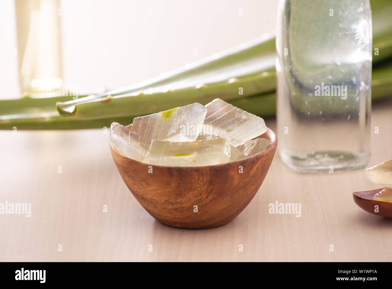 Ciotola con pelato aloe vera e foglie verdi su sfondo di legno Foto Stock