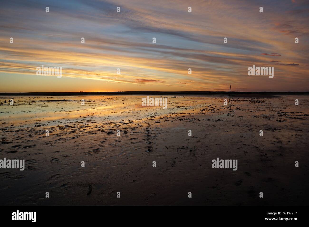 Cloud-presentano striature di colore arancione tramonto riflessi nel lago Tyrrell Foto Stock