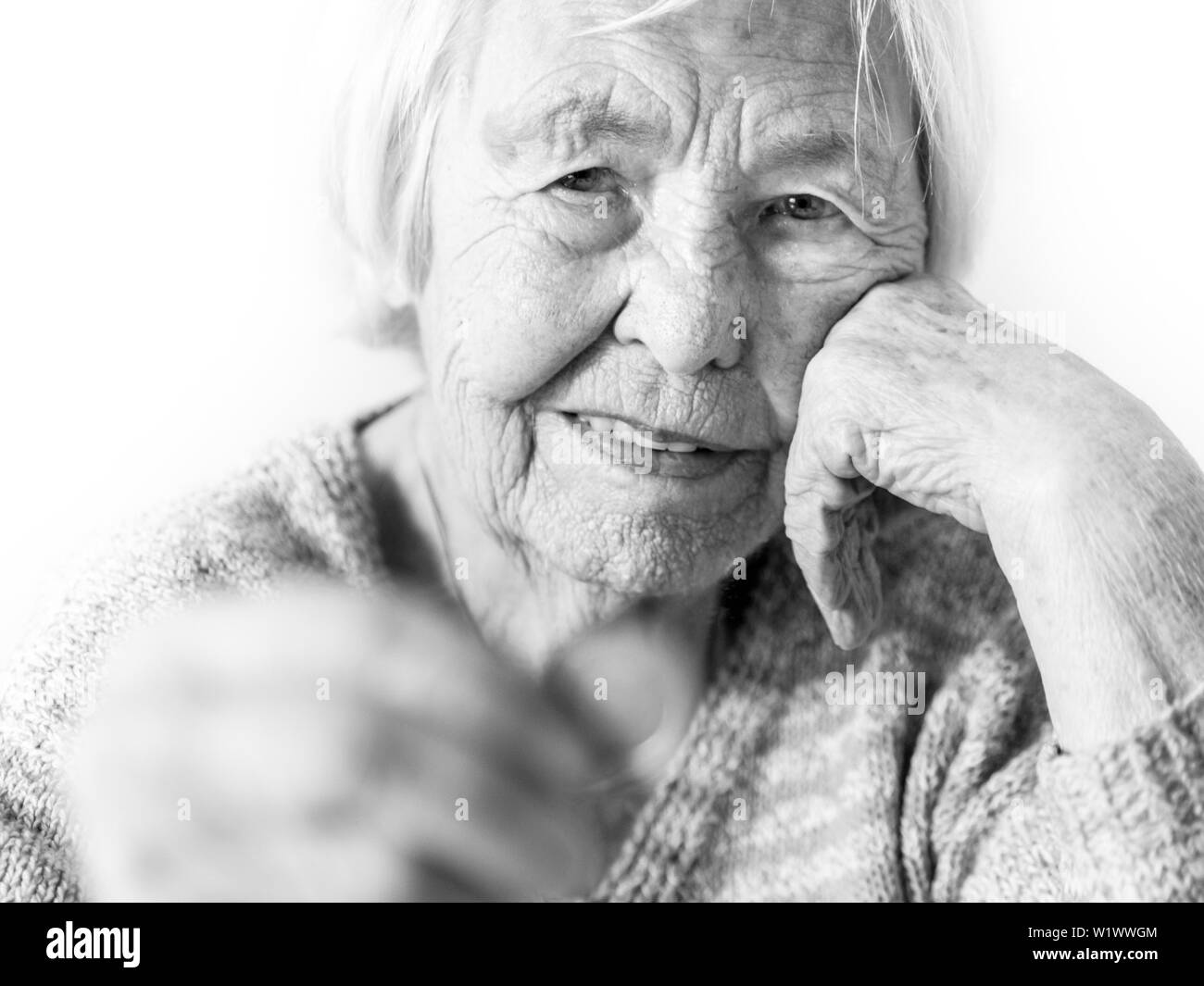 Allegro anziani 96 anni donna seduta al tavolo a casa felici con una moneta in mano. Il risparmio per il pensionamento e finanziari il concetto di planata in Foto Stock