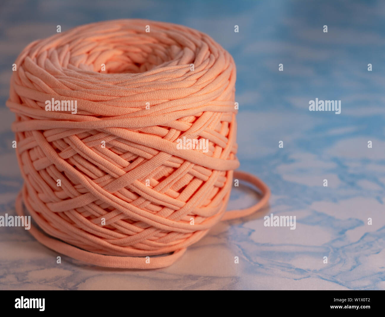 Hobby e attività creative concetto - una bobina di grandi dimensioni filo di maglia di pesca del colore sulla superficie del marmo blu, close up, full size. Foto Stock