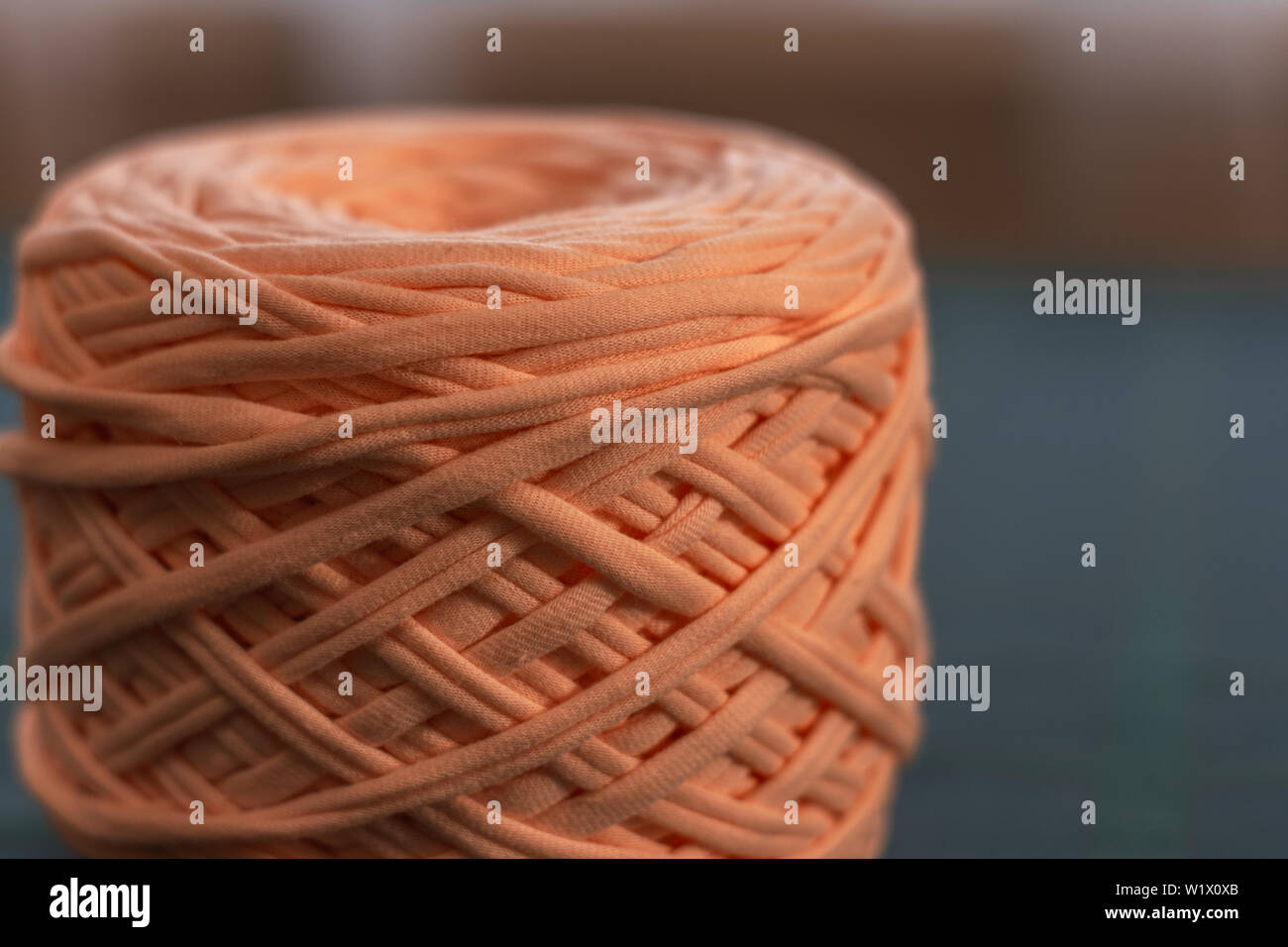 Hobby e attività creative concetto - una bobina di grandi dimensioni filo di maglia di colore pesca in backgroud blure, close up, full size. Foto Stock