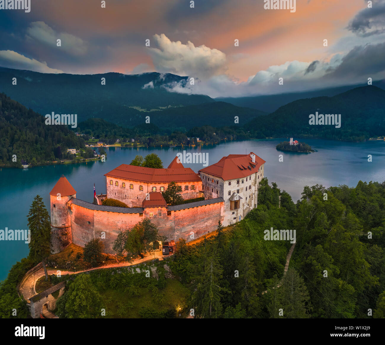 Bled, Slovenia - Vista aerea della bella illumina il castello di Bled (Blejski Grad) con la chiesa dell Assunzione di Maria e Alpi Giulie a backgro Foto Stock