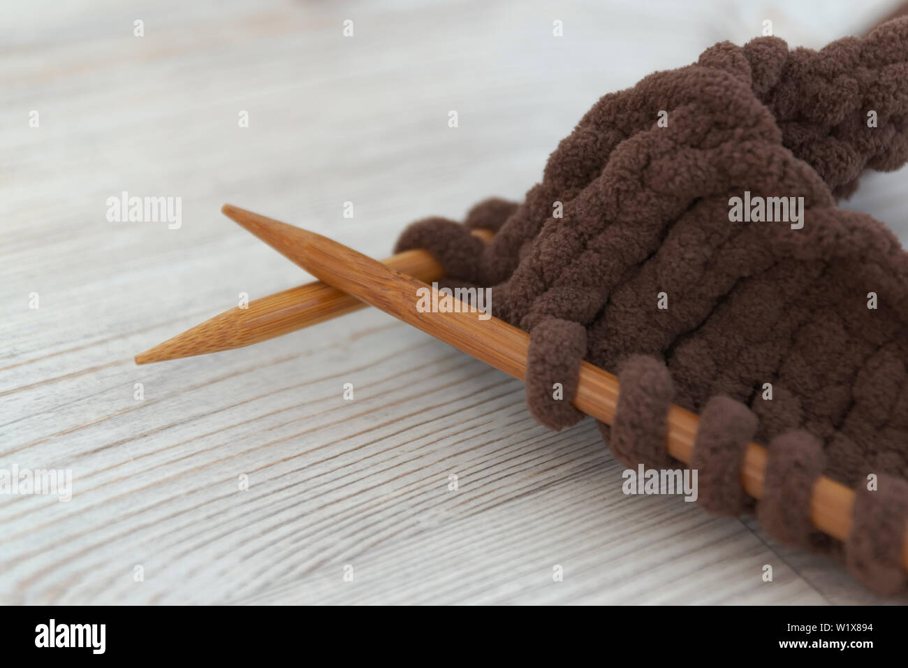 Legno aghi di tessitura e lavorazione a maglia da spesso di filo marrone. Close-up. Uso come una dimostrazione di artigianato femminile Foto Stock