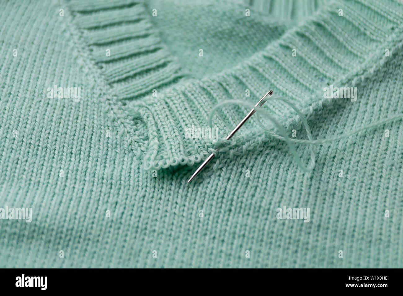 Primo piano di una V-collare realizzato dal verde di lana. Maglia non finito. Foto Stock