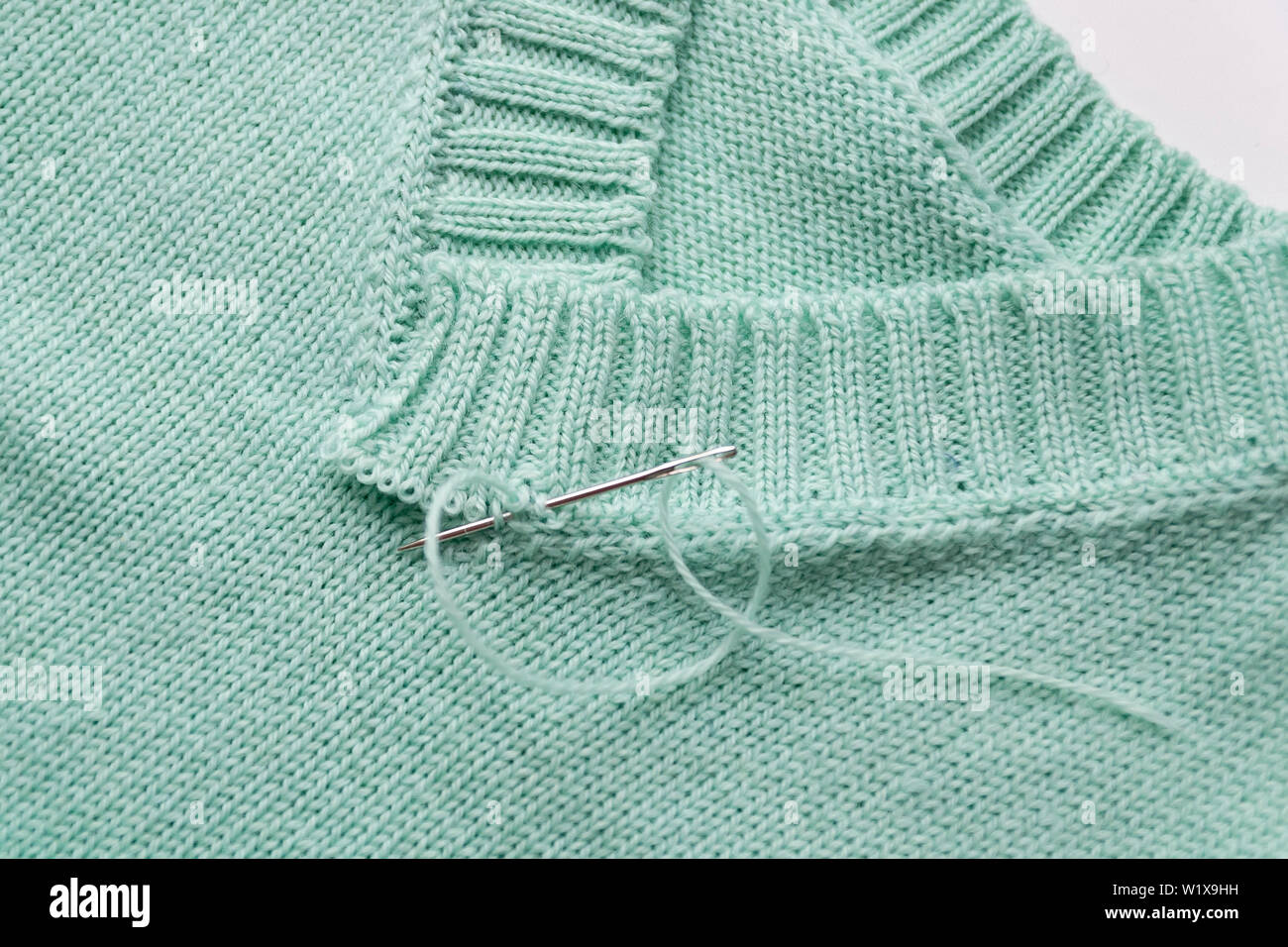 Primo piano di una V-collare realizzato dal verde di lana. Maglia non finito. Foto Stock