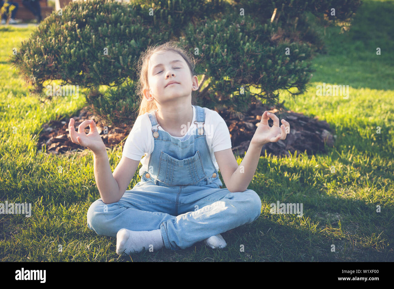 Una ragazza con gli occhi chiusi è la meditazione in un giardino giapponese. Calma e felice adolescente Foto Stock