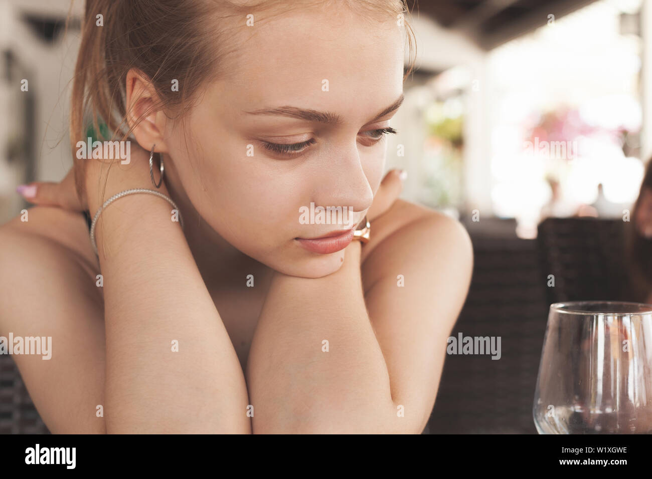 Giovane bella bionda Caucasian ragazza seduta in un ristorante mediterraneo con un bicchiere vuoto Foto Stock