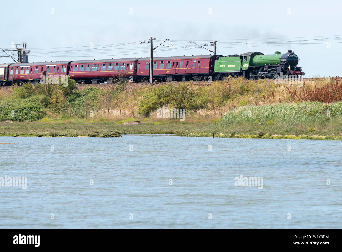 Un'escursione in treno a vapore va da Liverpool Street a Londra a Dereham nel Norfolk, passando attraverso la campagna dell'Essex e del Suffolk. Visto salire su un argine sopra il fiume Stour a Manningtree, Essex, lo speciale Steam Dreams Rail Co. Viene trasportato da 61306 LNER Thompson Classe B1 "Mayflower". Risplendente in verde mela BR la locomotiva è stata recentemente completamente revisionata e restituita ai principali prodotti speciali all'inizio del 2019 Foto Stock