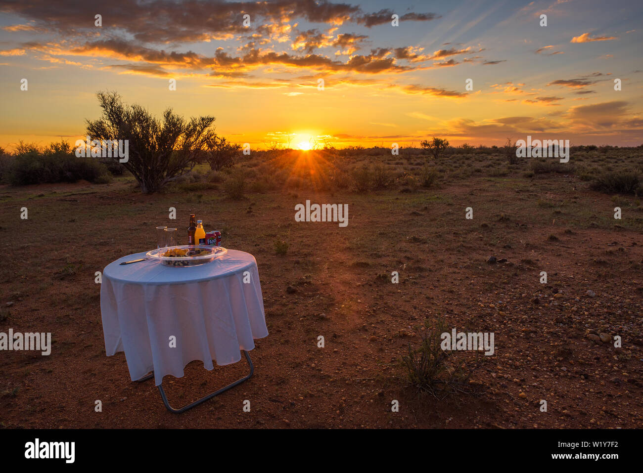 Tavolo da picnic con spuntini e bevande nel deserto del Kalahari al tramonto Foto Stock