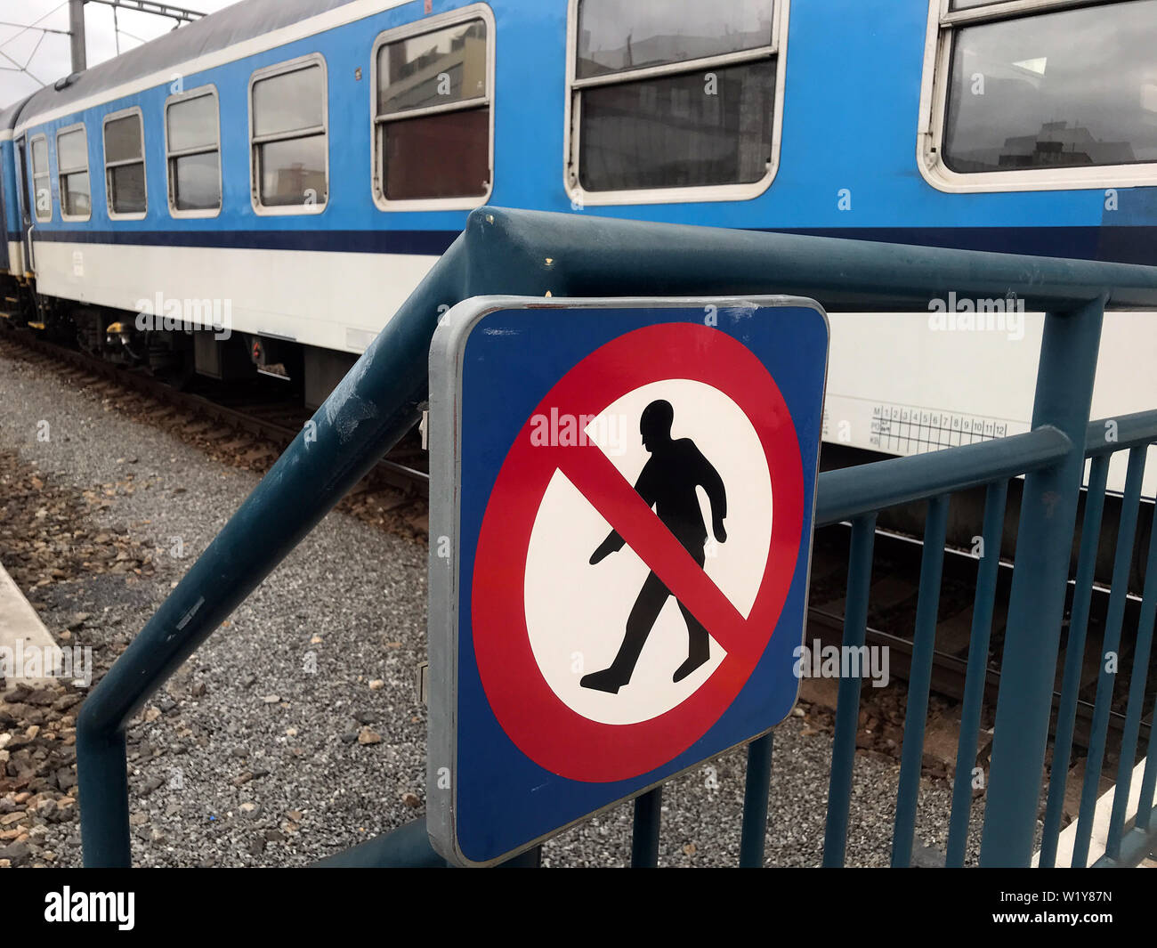 Indicazioni per il divieto di camminare per la via, il treno è in piedi sulle piste in background. Foto Stock