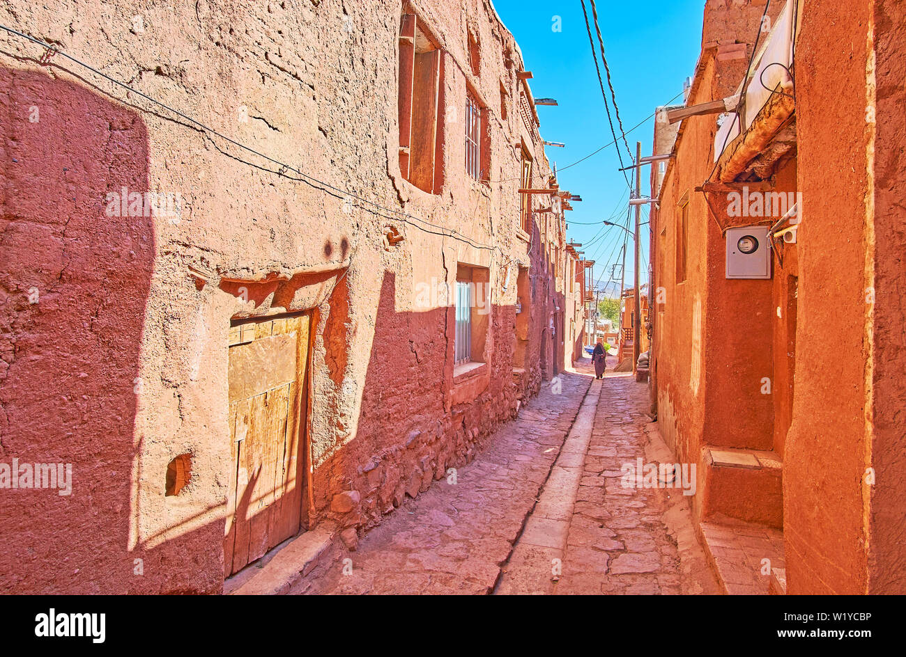 La stretta strada ombreggiata di Abyaneh village con conserva di vecchi edifici di rosso ocra di fango e pietre da Karkas montagne, Iran. Foto Stock
