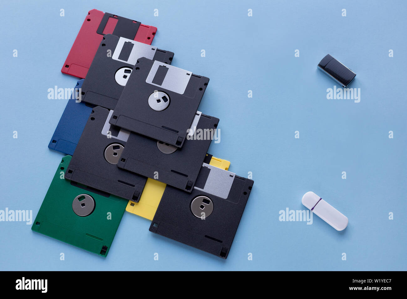 L'evoluzione dei dati digitali del dispositivo di storage. I dischi floppy vs piccole unità flash. Isolato su uno sfondo blu. Moderno e tecnologia retrò. Foto Stock