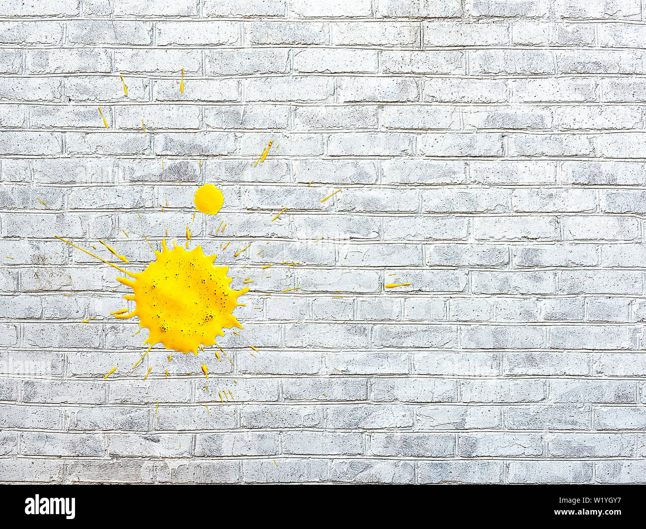Bianco parete di mattoni macchiati macchie di vernice di colore giallo Foto Stock