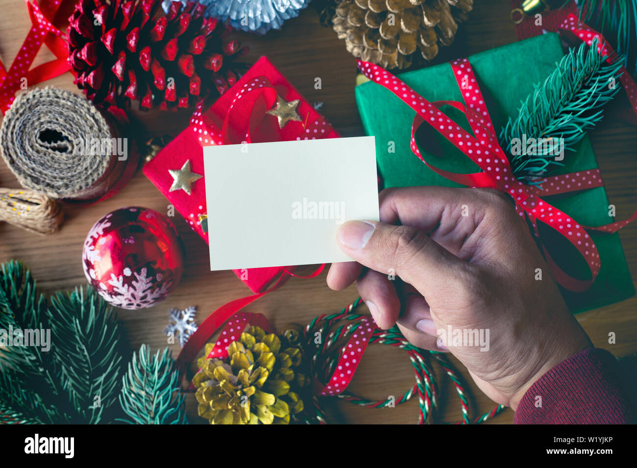 Buon Natale concetti umani con la scrittura a mano biglietti di auguri con confezione regalo presente e elemento di ornamento sulla tavola di legno sfondo.stagione invernale acti Foto Stock