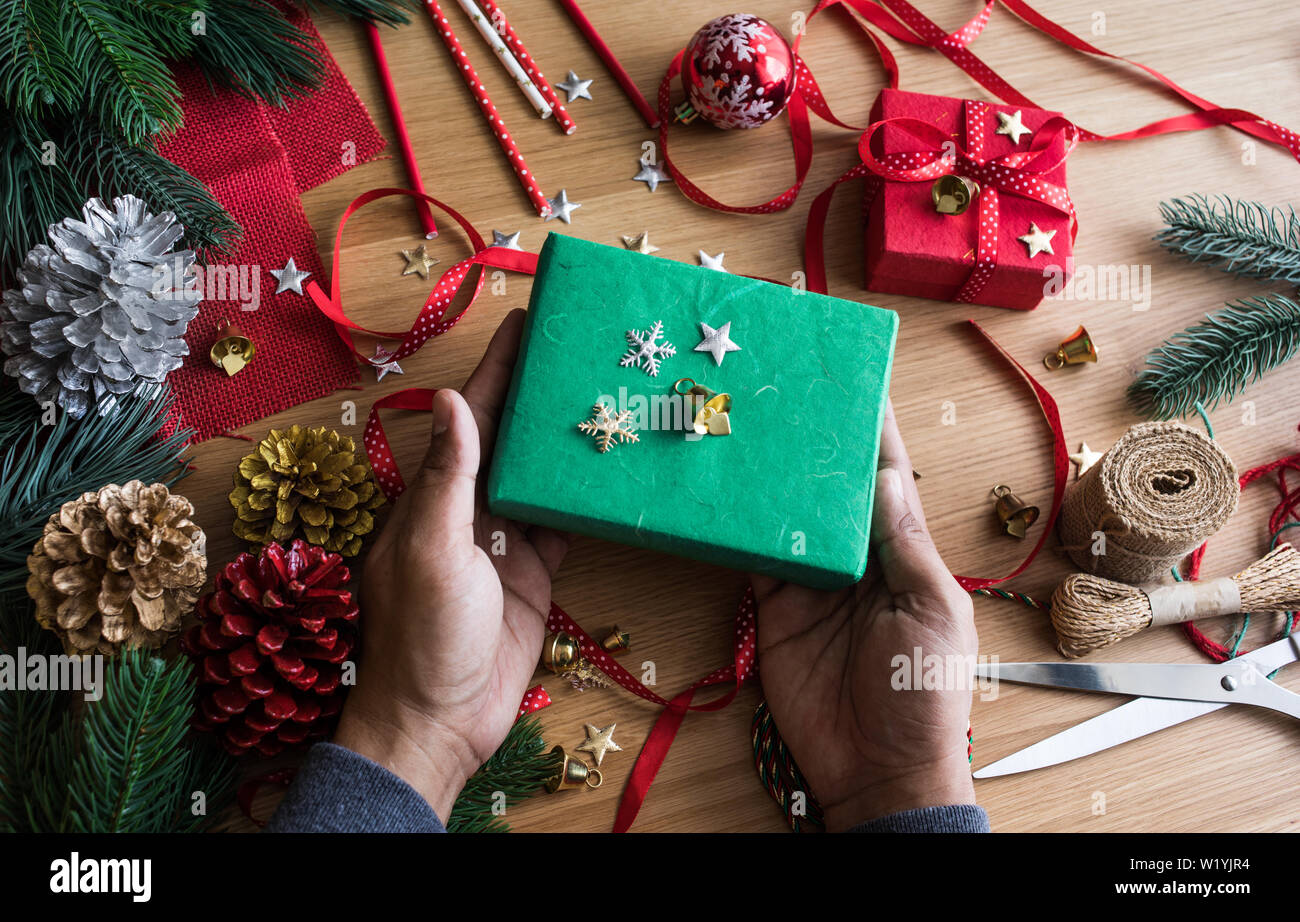 Buon Natale concetti con mano umana decorare confezione regalo presente e elemento di ornamento sulla tavola di legno sfondo.stagione invernale della auguri idee Foto Stock
