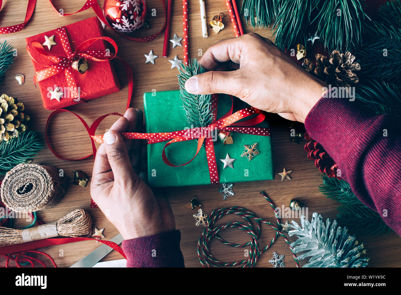 Buon Natale concetti con mano umana decorare confezione regalo presente e elemento di ornamento sulla tavola di legno sfondo.stagione invernale della auguri idee Foto Stock