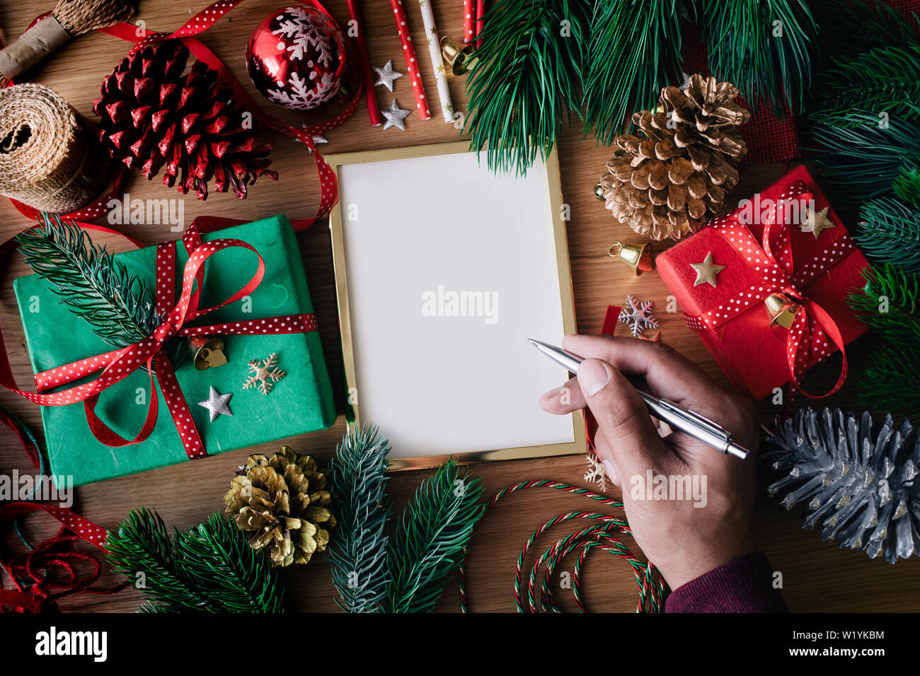 Buon Natale concetti umani con la scrittura a mano biglietti di auguri con confezione regalo presente e elemento di ornamento sulla tavola di legno sfondo.stagione invernale acti Foto Stock