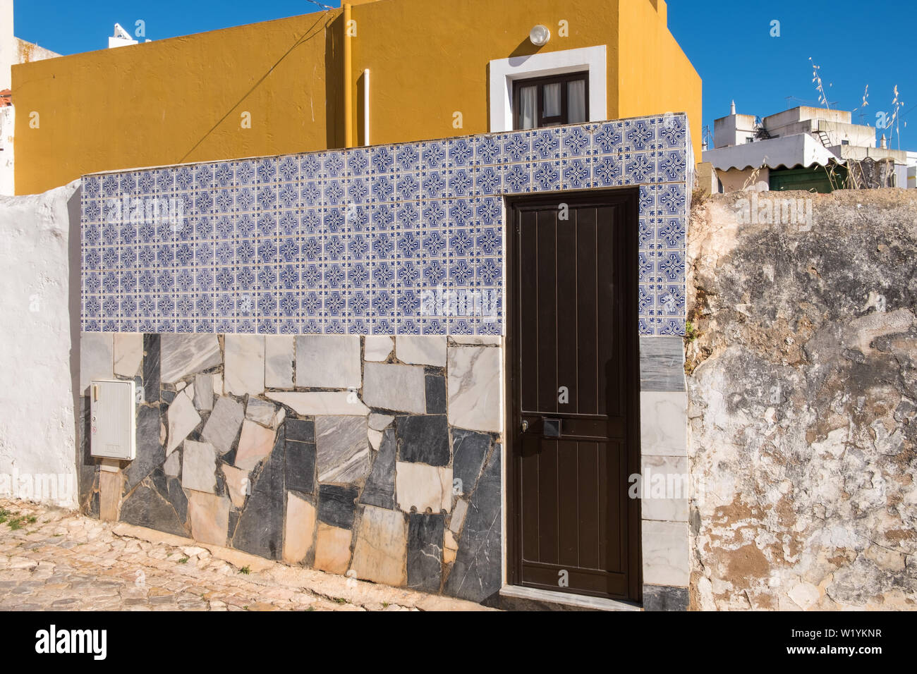 Nella parete anteriore della piccola casa coperto di lastre di marmo e piastrelle decorative in Alvor, Algarve, PORTOGALLO Foto Stock