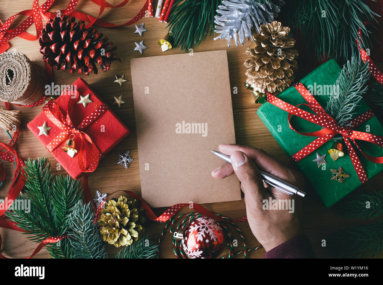 Buon Natale concetti umani con la scrittura a mano biglietti di auguri con confezione regalo presente e elemento di ornamento sulla tavola di legno sfondo.stagione invernale acti Foto Stock