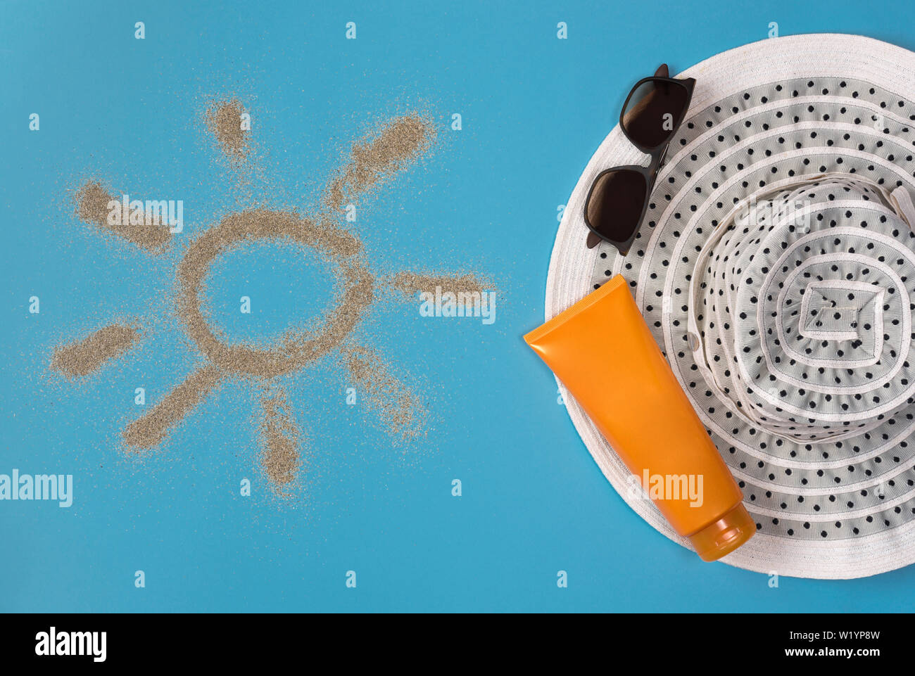 Dipinto di sun, cappello, crema solare e occhiali da sole su sfondo blu. Vista dall'alto. Tema la spiaggia su sfondo blu. Foto Stock