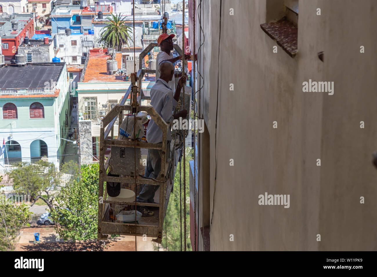 L'Avana, Cuba - Maggio 21, 2019: uomo cubano sta lavorando su una fase di rotazione sul lato di un edificio nella città dell'Avana durante una calda giornata di sole. Foto Stock
