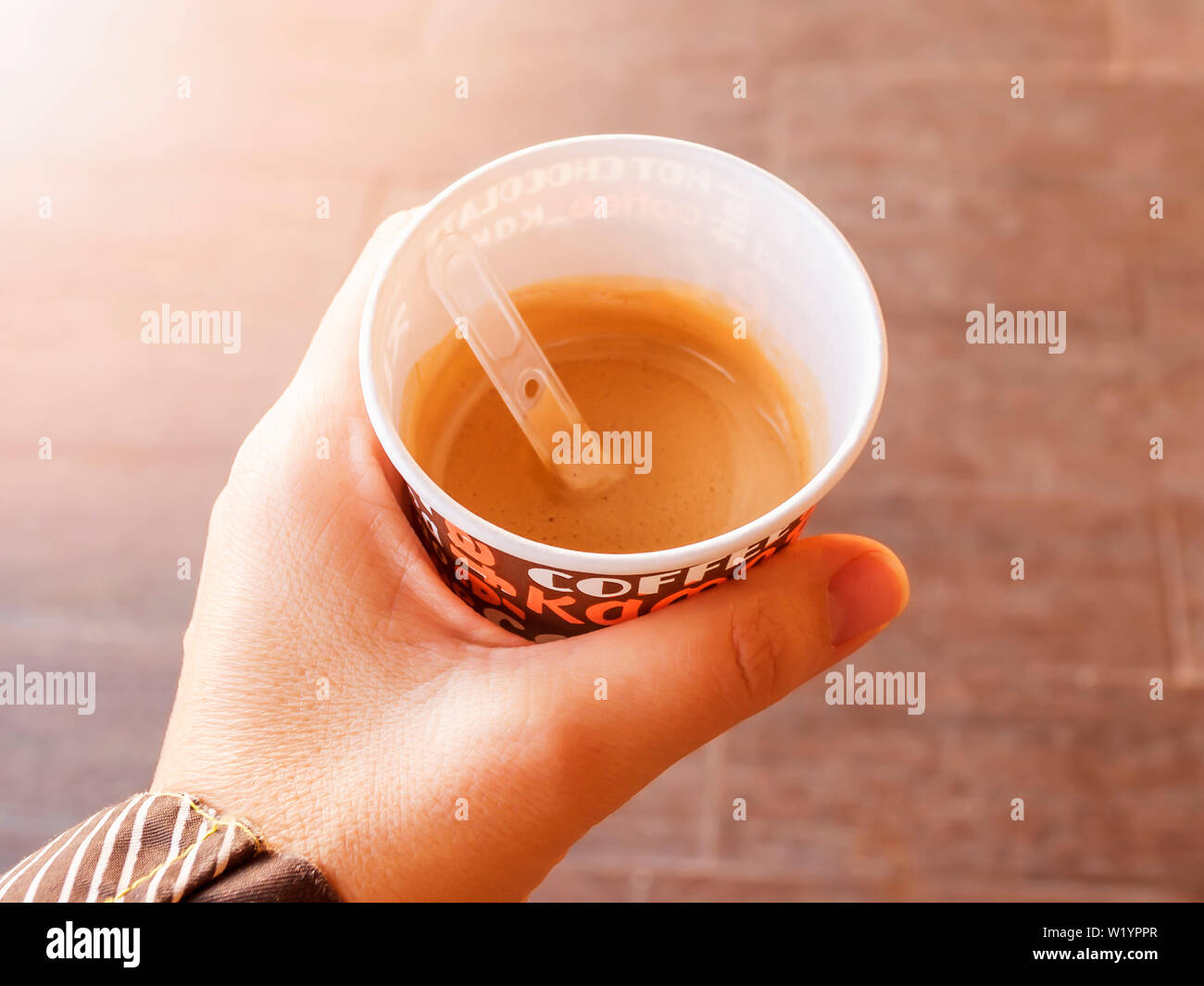 Donna mano che regge una tazza di cartone con il caffè. Caffè caldo dal distributore automatico all'aperto la macchina per il caffè. Close-up. Vista dall'alto. Foto Stock