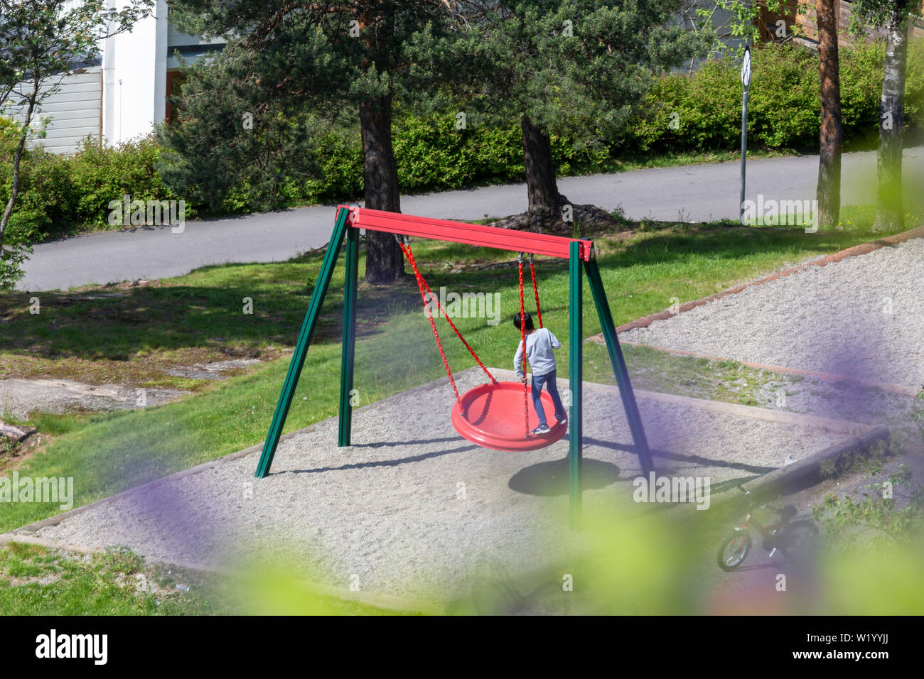 Little Boy giocando su Flying Saucer in un parco giochi urbano vicino a casa Foto Stock