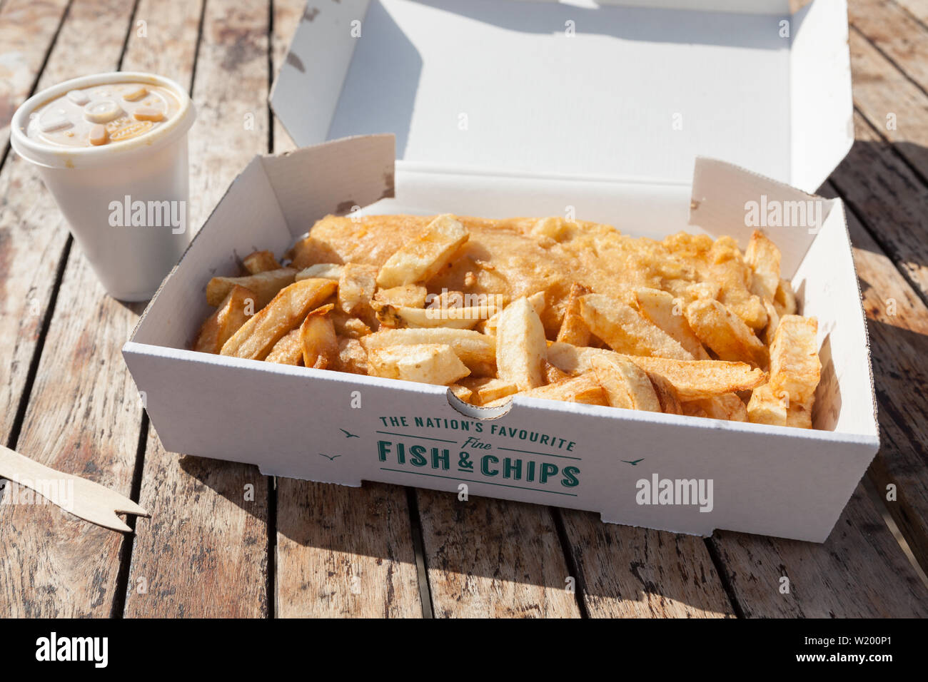 Britannico tradizionale pesce e patatine in una casella su un tavolo di legno. Foto Stock