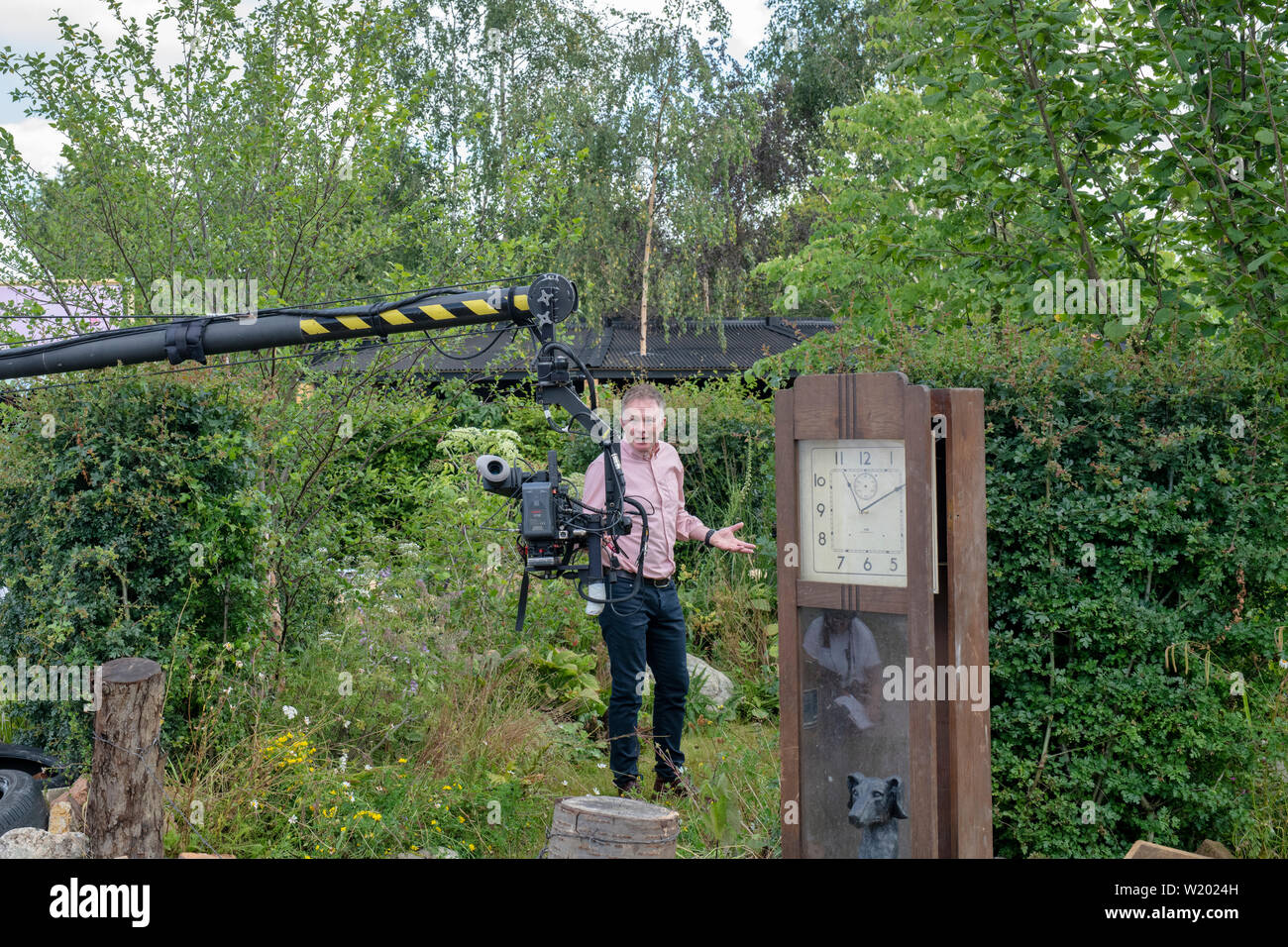 Toby Buckland facendo un pezzo alla telecamera nella calma contro il caos mostra giardino alla RHS Hampton Court flower show 2019. Hampton Court Palace, Surrey, Regno Unito Foto Stock
