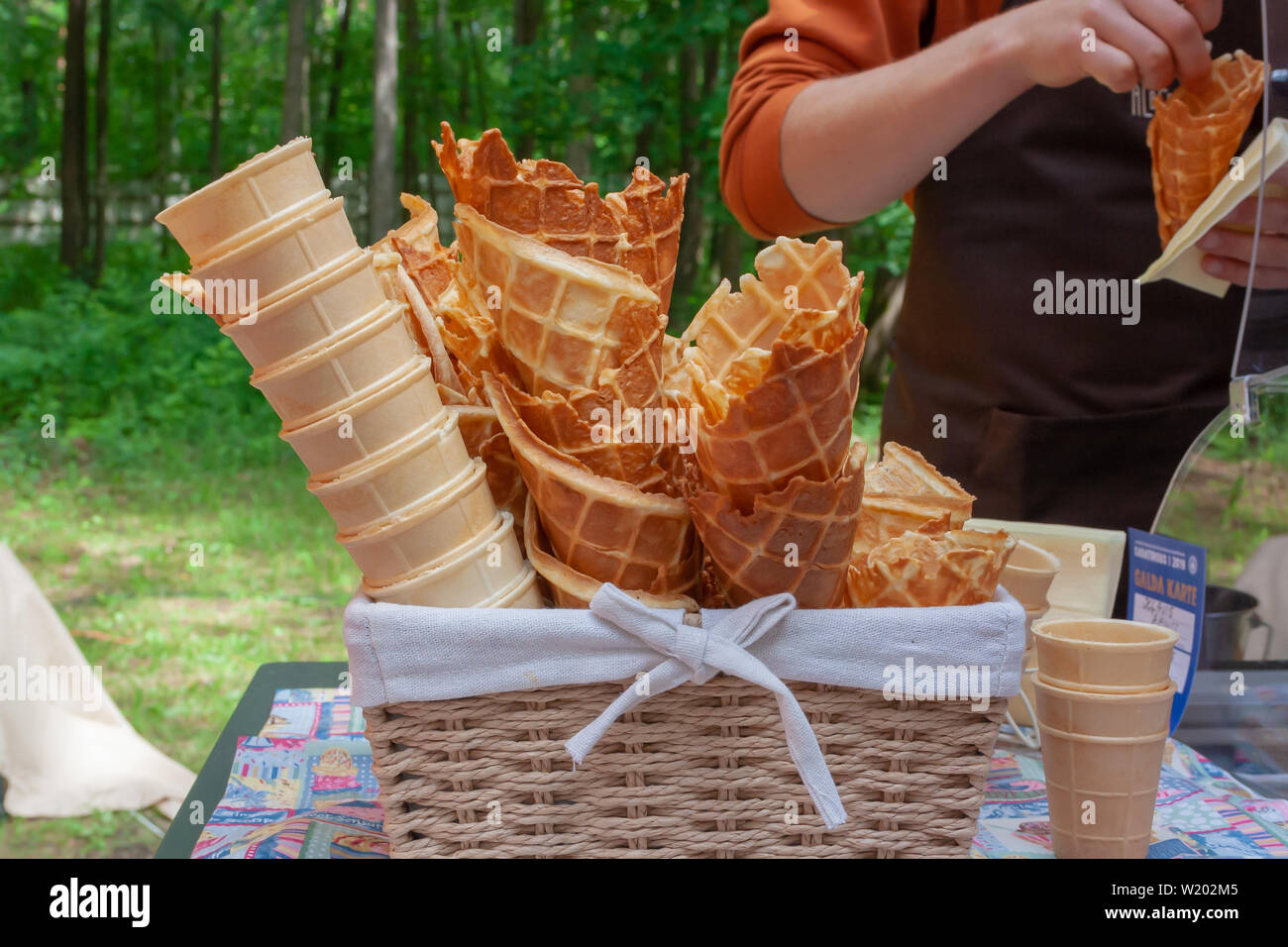Coni gelato in un ceppo di legno cesto di vimini in una pasticceria. Estate dessert concept Foto Stock
